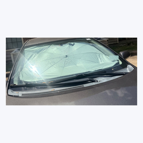 Luvenzo AutoShade sun shade umbrella installed behind the windshield of a real car, seen from outside on a sunny day